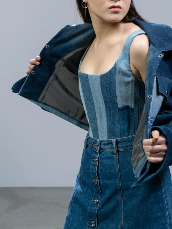 Model membuka jaket denim biru tua di atas bustier tambal