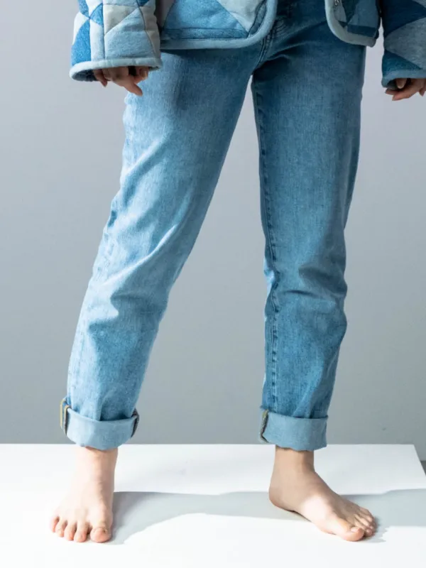 Kaki model memakai jeans biru muda berpinggang tinggi dengan ujung digulung