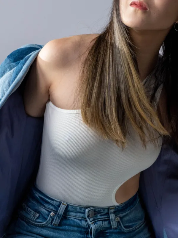 Model memakai kaus rib putih tanpa lengan dengan jaket tambal tersampir di bahu