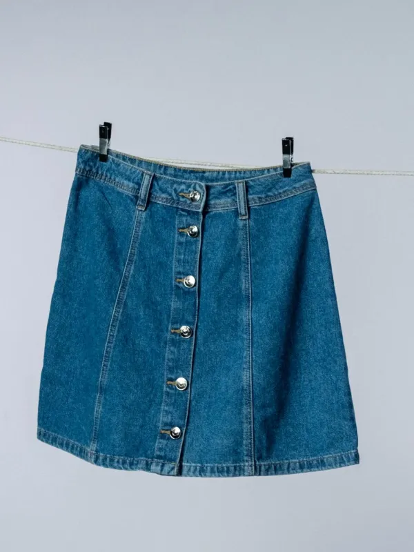 Rok denim A-line dengan deretan kancing besi di depan, tergantung di tali jemuran