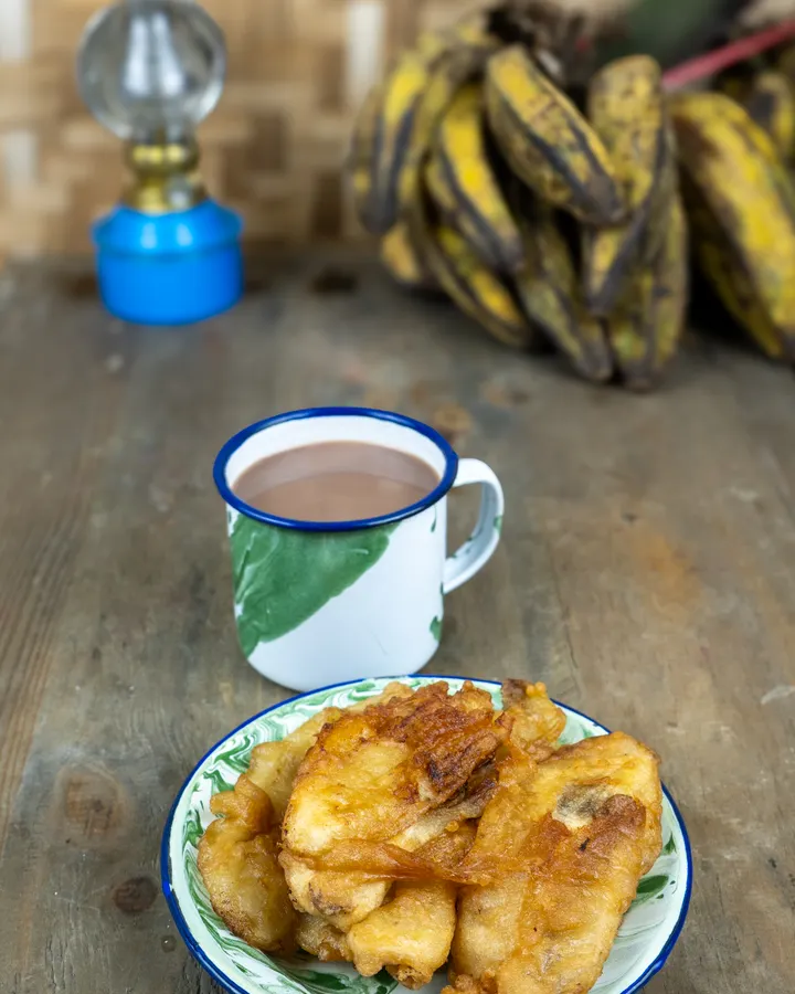 Cokelat panas dalam cangkir email hijau putih dengan sepiring pisang goreng