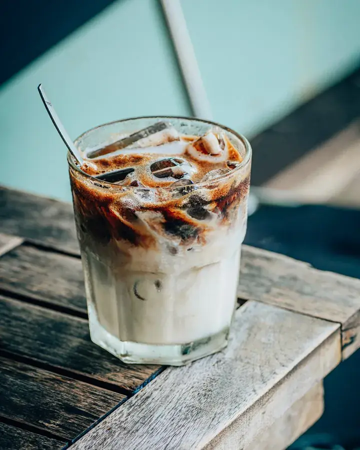 Es kopi susu gula aren dalam gelas bening di atas meja kayu