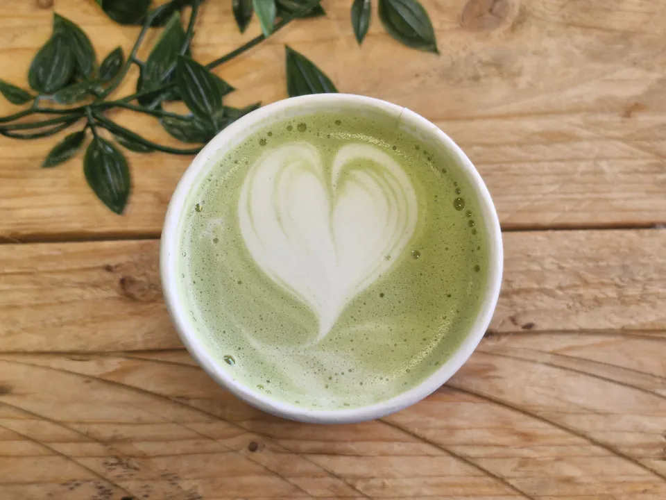 Matcha latte dengan latte art berbentuk hati di meja kayu
